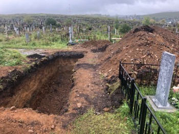 «Выглядит жутко»: зачем на cаткинском кладбище вырыли огромную яму на дороге? 